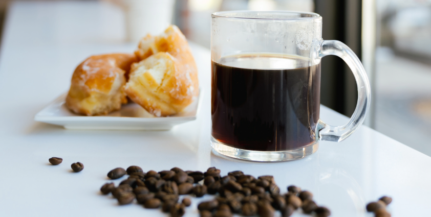 Coffee beans, coffee and pastries on a counter